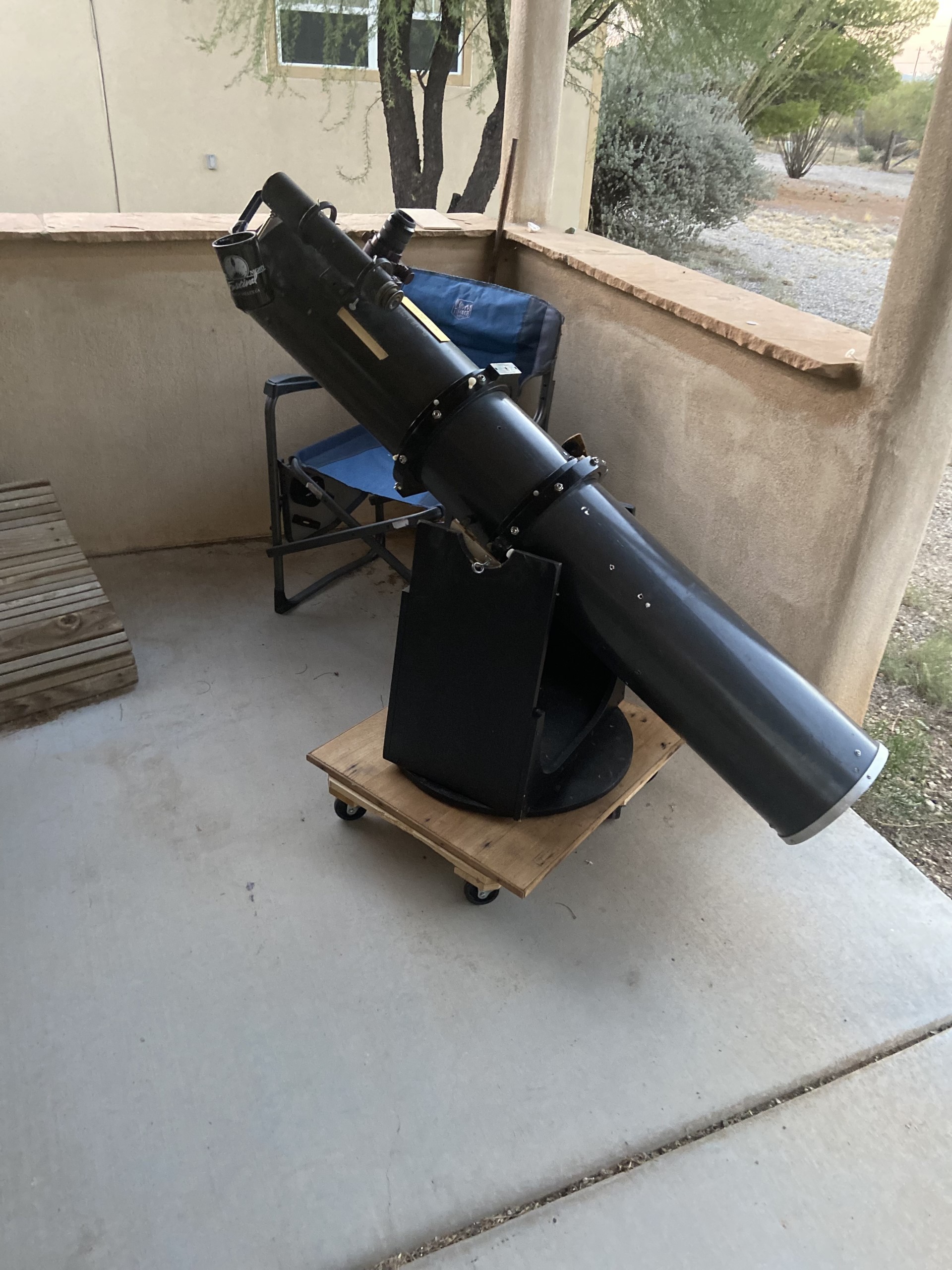 An image of a large Dobsonian style telescope on a back porch.
